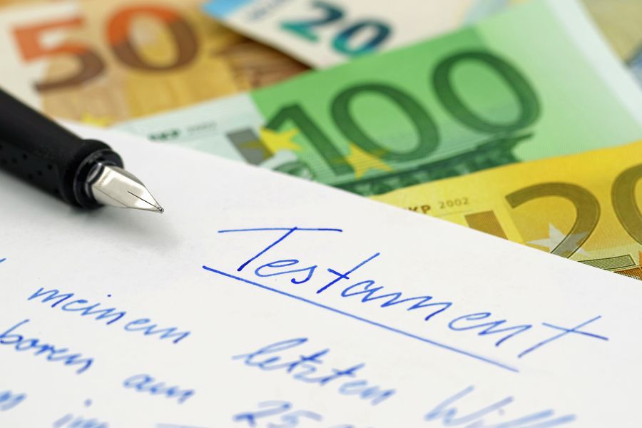 Handgeschriebenes Testament mit Schreibfeder und Euroscheinen im Hintergrund